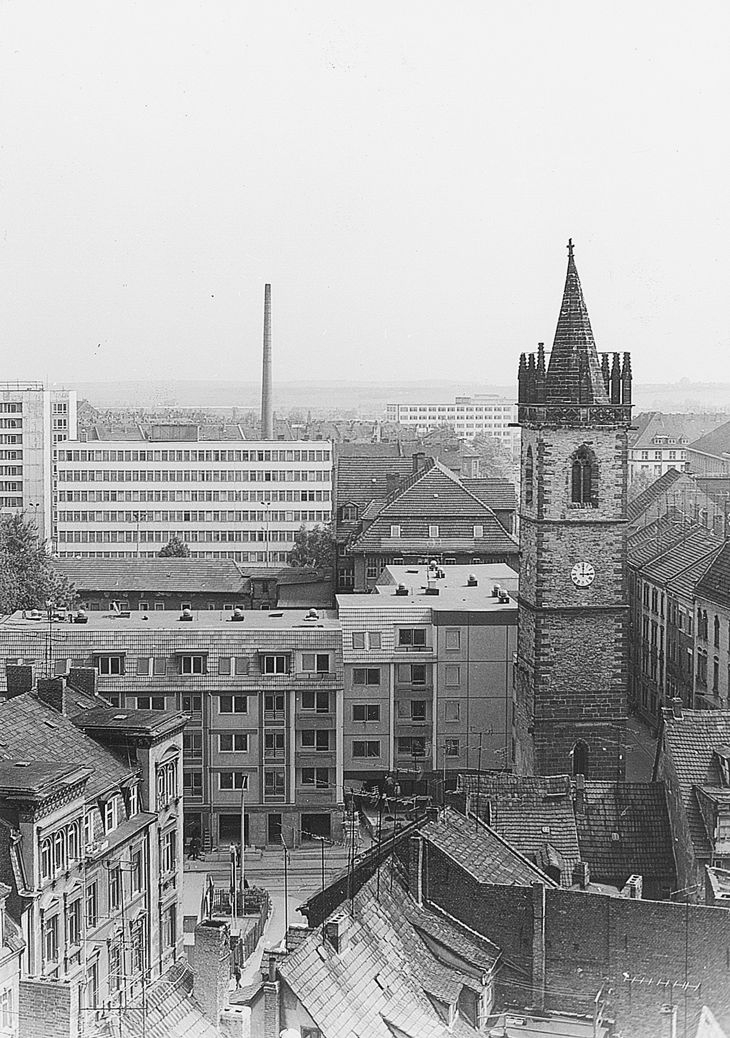 Blick über die Erfurter Altstadt mit einem historischen Kirchturm neben DDR-Neubauten